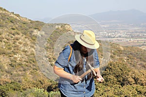 Latin adult woman geologist studies the details and characteristics of rocks, minerals and fossils in the mountain