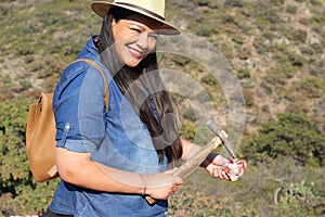Latin adult woman geologist studies the details and characteristics of rocks, minerals and fossils in the mountain