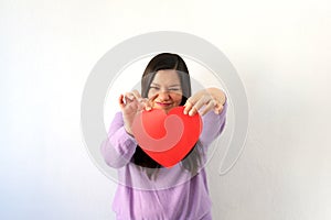 Latin adult woman with red heart shows her sadness, anger and unhappiness for the arrival of February and celebrating Valentine`s