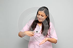 Latin adult woman shows the use of the oximeter she puts it on the finger of her hand to measure her oxygenation due to suspicion