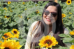 Latin adult woman with sunglasses walks through a field of sunflowers forgets her problems full of happiness in fullness, with tra