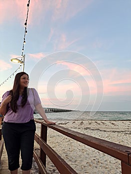 Latin adult woman walks along the boardwalk of Puerto Progreso in Yucatan, Mexico, enjoys the sunset on her vacation photo