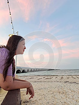 Latin adult woman walks along the boardwalk of Puerto Progreso in Yucatan, Mexico, enjoys the sunset on her vacation photo