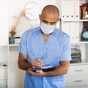 Portrait of friendly male doctor or nurse wearing blue scrubs uniform and stethoscope