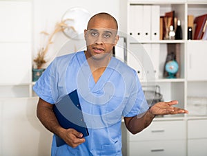 Portrait of friendly male doctor or nurse wearing blue scrubs uniform and stethoscope