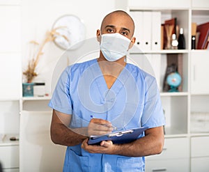 Portrait of friendly male doctor or nurse wearing blue scrubs uniform and stethoscope