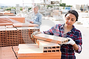 Latin american female worker holding redbricks at warehouse