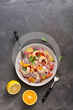 Latin American food. Ceviche salad with shrimps and oranges on a dark rustic background. Top view, flat lay, copy space