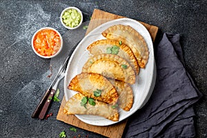 Latin American fried empanadas with tomato and avocado sauces. Top view