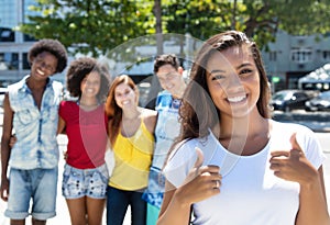 Latin american girl showing thumb with group multi ethnic people