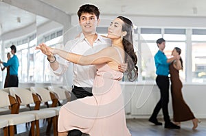 Latin American guy and dark-haired girl performing kizomba in dance studio