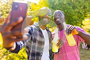 latin american people spending evening sunset together in summer park taking self photos on camera of smartphone