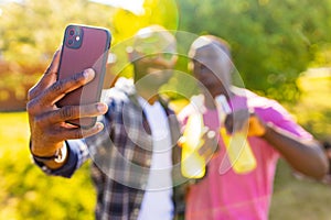 latin american people spending evening sunset together in summer park taking self photos on camera of smartphone