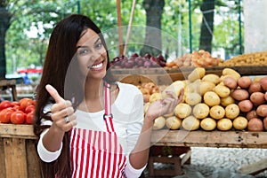 Latin american saleswoman at farmers market with potato and vegetables
