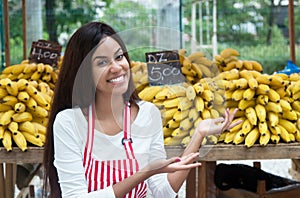 Latin american saleswoman at farmers market presenting bananas
