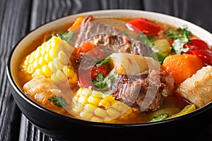 Latin American Sancocho thick meat soup with vegetables close-up on a plate on the table. horizontal photo