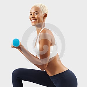 Latin American smiling woman lifts dumbbells, young female athlete doing fitness workout, engaged in physical activity to improve