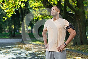 Latin american sportsman resting after jogging in the park and exercising, closed his eyes and listens to music and