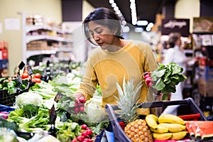 Latin american woman choosing red radish in supermarket