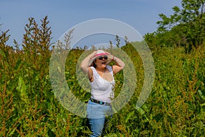 Latin American woman holding hat on head with her hands to prevent the wind from blowing it, surprised expression