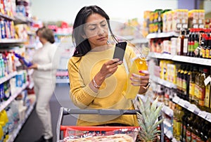 Latin american woman scanning barcode of products in store