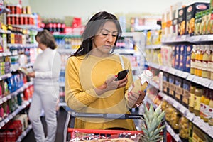 Latin american woman scanning barcode of products in store