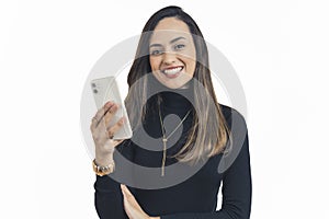 Latin american young adult woman wearing black turtleneck looking into camera similing and holding smartphone. Modern