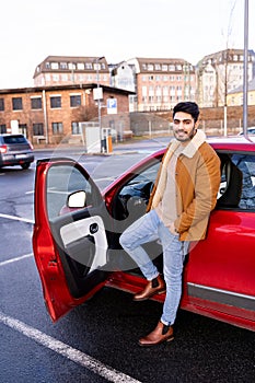 Latin or arab man standing near car with opened door on parking slot of city