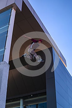 Latin boy dressed in red. Man practicing an extreme activity. Young man practicing parkour jumping from one building to another