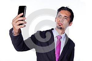 Latin businessman taking a selfie. Young adult brown skinned man using smart phone to take a selfie, isolated on all