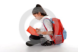 Latin child reading textbook or notepad smiling sitting on the floor