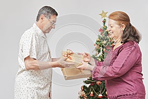 Latin couple celebrating holidays at home together, exchanging Christmas gifts