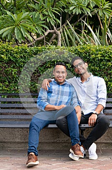 Latin couple gay men sitting on a bench, gay concept