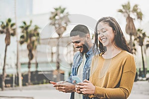 Latin couple shopping online using smartphone app - Young people having fun with new e-commerce technology trend - Social network