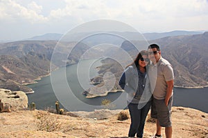 Latin couple with sunglasses in the viewpoint El Vigilante, in the background the Zimapan dam in Hidalgo Mexico