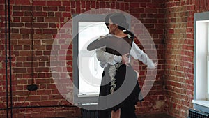 Latin dances - a couple training pair dance in the studio with brick walls