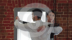 Latin dances - man and woman training their dance in the studio with brick walls - the man counting the tempo