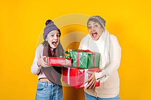 Latin family grandmother and granddaughter holding christmas gift on yellow background in Mexico Latin America