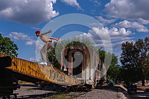 Latin fitness man on an abandoned train. Hispanic man about to do a somersault. Latino boy practicing stunts in a park with
