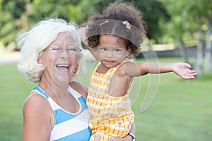 Latin girl and her caucasian grandmother hugging in a park