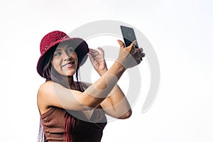 Latin girl taking a picture with her mobile phone. Portrait of a Colombian girl on a white background. using app