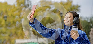 Latin girl taking a selfie with her mobile phone in a public park with copy space