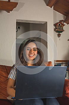 Latin girl working from home, from her computer she does different things. She works with a laptop, smartphone and notebook