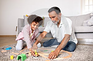 Latin Grandpa And Grandson Playing With Toys In Living Room