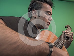 Latin guy playing guitar very serious