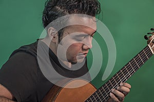 Latin guy playing guitar very serious