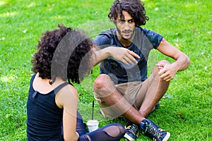 Latin Hipster couple sitting on meadow