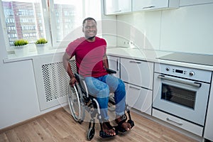 Latin hispanic man sit on wheel chair at kichen and looking at camera