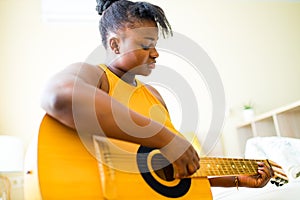 Latin hispanic woman learning to play on guitar