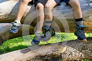 latin kids sitted on a tree trunk with mountain boots